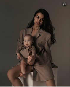 a woman holding a baby in her lap while posing for a photo with the photographer