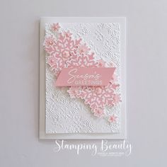 a white card with pink flowers and a ribbon on the front that says seasons's greetings