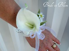 a bride and groom holding hands with white flowers on their wrists at the end of their wedding day