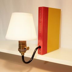 a lamp is sitting on a shelf next to a yellow book and a red book