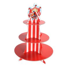 three tiered red and white cake stand with circus theme on the top, in front of a white background