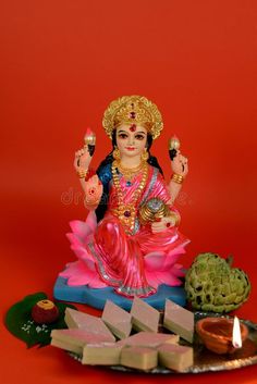 a small statue of the hindu god sitting on a plate with sweets and crackers in front of it