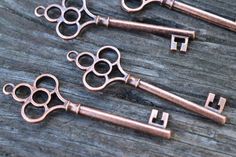 three antique style keys are sitting on a wooden surface