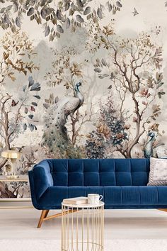 a blue couch sitting in front of a wall with trees and birds painted on it