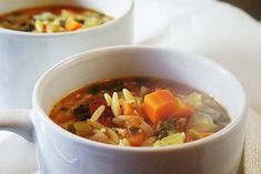 two white bowls filled with soup on top of a table