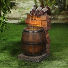 a wooden barrel filled with water on top of a lush green field next to a brick wall