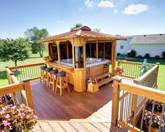 an outdoor hot tub on a deck with bar stools and flowers in the foreground