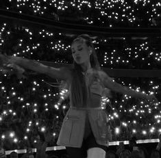 a woman standing on top of a stage with her arms outstretched in front of an audience