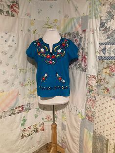 "Embroidered turquoise blouse. 100% manta (raw cotton). no stretch. M. SEE MEASUREMENTS BELOW.  Well made in great condition.  Sleeve length from neck opening 8.5\" Bust 42\" Hips 42\" Length from center back 23\" Dress Form is 36-26-37 My home is smoke free. Clothing is measured while laying flat and unstretched. I highly recommend taking the time to measure something that fits you well for comparison. Remember that you need breathing room that is not included in the measurements.  Any flaws ar Light Blue Short Sleeve Top With Floral Embroidery, Casual Turquoise Cotton Blouse, Light Blue Short Sleeve Cotton Blouse, Light Blue Cotton Blouse With Short Sleeves, Blue Cotton Shirt With Floral Embroidery, Traditional Cotton Crew Neck Top, Traditional Crew Neck Cotton Top, Blue Folk Style Short Sleeve Blouse, Blue Floral Embroidered Crew Neck Top