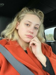 a woman sitting in the back seat of a car with her hand on her chin