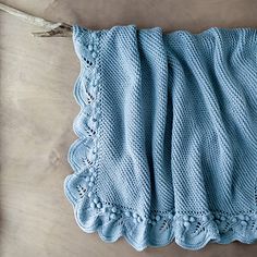 a blue knitted blanket laying on top of a wooden table