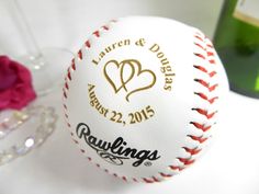 a baseball with the names and date engraved on it next to a wine glass filled with red roses