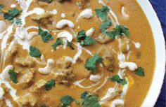 a white bowl filled with food and garnished with cilantro, cashews and parsley