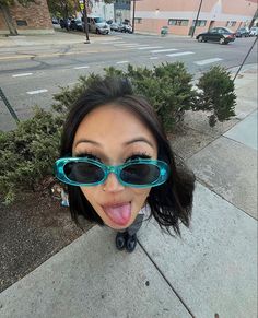 a woman sticking her tongue out with sunglasses on top of her head and the street in the background