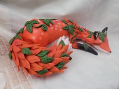 two orange figurines sitting on top of a white cloth covered tablecloth next to scissors