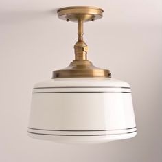 a white and gold light hanging from a ceiling fixture with a black stripe on the bottom