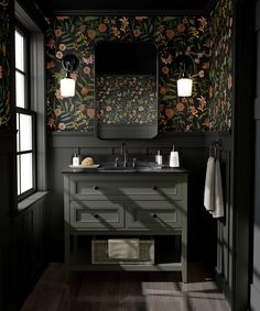 a bathroom with floral wallpaper and dark green cabinetry, along with two sinks