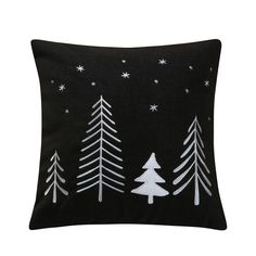 a black pillow with white trees and stars on the front, against a dark background