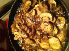 a pan filled with mushrooms and sauce on top of a stove