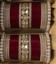 two red and gold bangles are sitting in a box with pearls on the sides