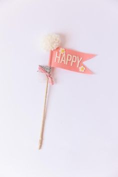 a pink happy sign on a stick with a white flower and a ribbon around it