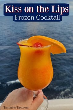 a person holding up a glass with an orange drink in it and the words, kiss on the lips frozen cocktail