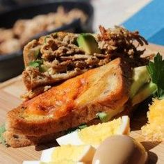 some food is laying out on a cutting board next to eggs and other foodstuffs