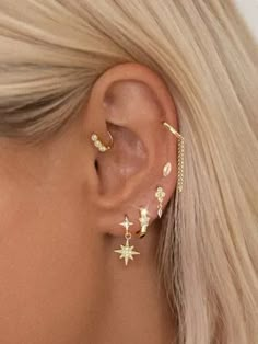 a woman with blonde hair wearing gold stars and moon ear climbrs in front of her ear