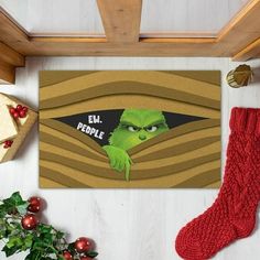 the grin face is peeking out from behind a door mat with christmas decorations around it