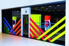 an entrance to a clothing store with neon colors on the walls and doors, along with mannequins dressed in brightly colored clothes