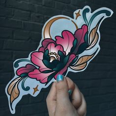 a person holding up a sticker with flowers on it in front of a brick wall