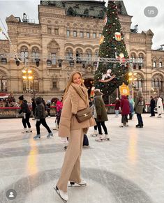 a woman is standing on an ice rink in front of a christmas tree with lights