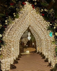 an archway decorated with christmas lights and greenery for a wedding or special event in the evening