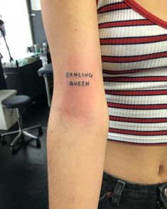 a woman's arm with the words dancing queen tattooed on it, in black ink