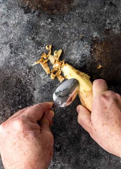 a person is peeling something off of a banana peel with a spoon on the side