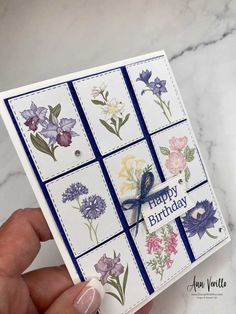 a hand holding a card with flowers on it and the words happy birthday written in blue