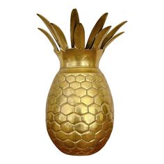 a gold pineapple shaped vase sitting on top of a white surface with no one around it