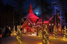 a house with christmas lights on it and trees in the front yard, lit up at night