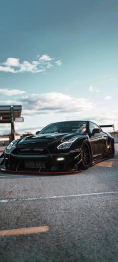 a black sports car parked on the side of an empty parking lot next to a bench