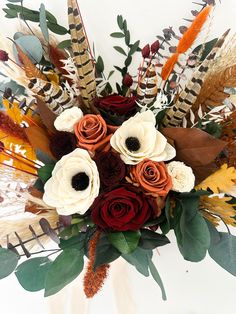 a vase filled with flowers and feathers on top of a table