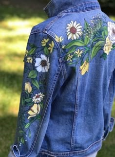 the back of a woman's jean jacket with flowers painted on it