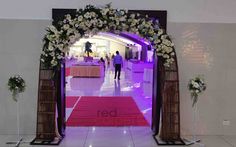 a red carpeted entrance way with white flowers and greenery on either side, leading to the reception area