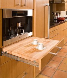 a kitchen with wooden cabinets and tile flooring is shown in this image, there are two cups on the counter