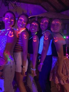 a group of young women standing next to each other in front of a purple light