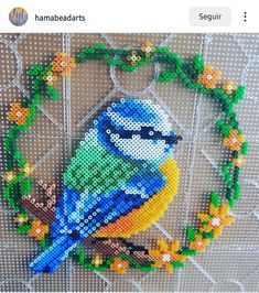 a beaded bird sitting on top of a wooden table next to a green wreath