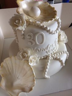 a white cake decorated with pearls and seashells