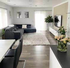 a living room filled with furniture and flowers on top of a wooden floor covered in white rugs