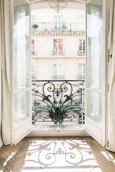 an open window with the view of a balcony and building in the background, on a sunny day