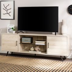 a flat screen tv sitting on top of a wooden entertainment center next to a clock