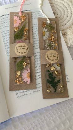 two bookmarks with flowers and words on them sitting on top of an open book